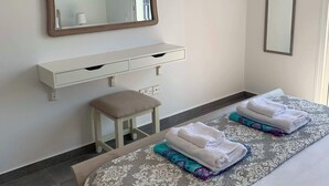 Une chambre d’hôtel avec un lit, une table de chevet, une chaise, un miroir et une fenêtre.