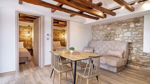 A cozy living room with a stone wall, a wooden ceiling, and a beige sofa. - Theros Easy Living (Thasos)