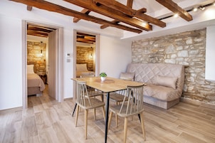 Una sala de estar acogedora con pared de piedra, techo de madera y sofá color beige.