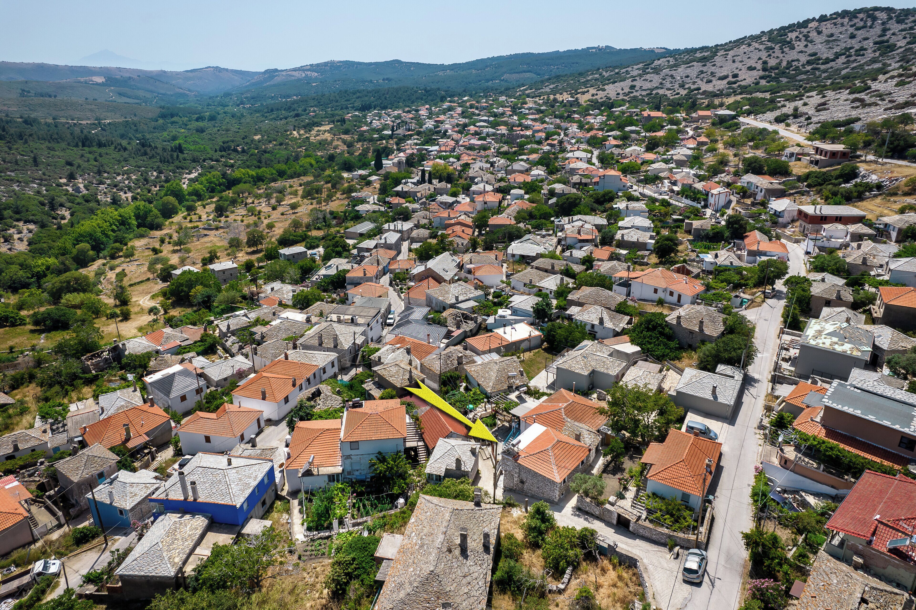 Una vista aerea di una zona residenziale densamente popolata, con case ravvicinate, strette vie e vegetazione circostante.