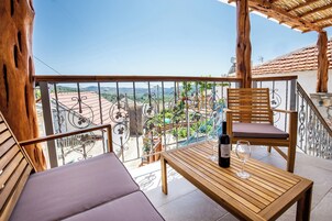 Un balcón con una mesa de madera, una silla y una botella de vino.