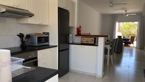 Eine moderne Küche mit weißen Schränken, einer schwarzen Arbeitsplatte und einem Essbereich mit Tisch und Stühlen.