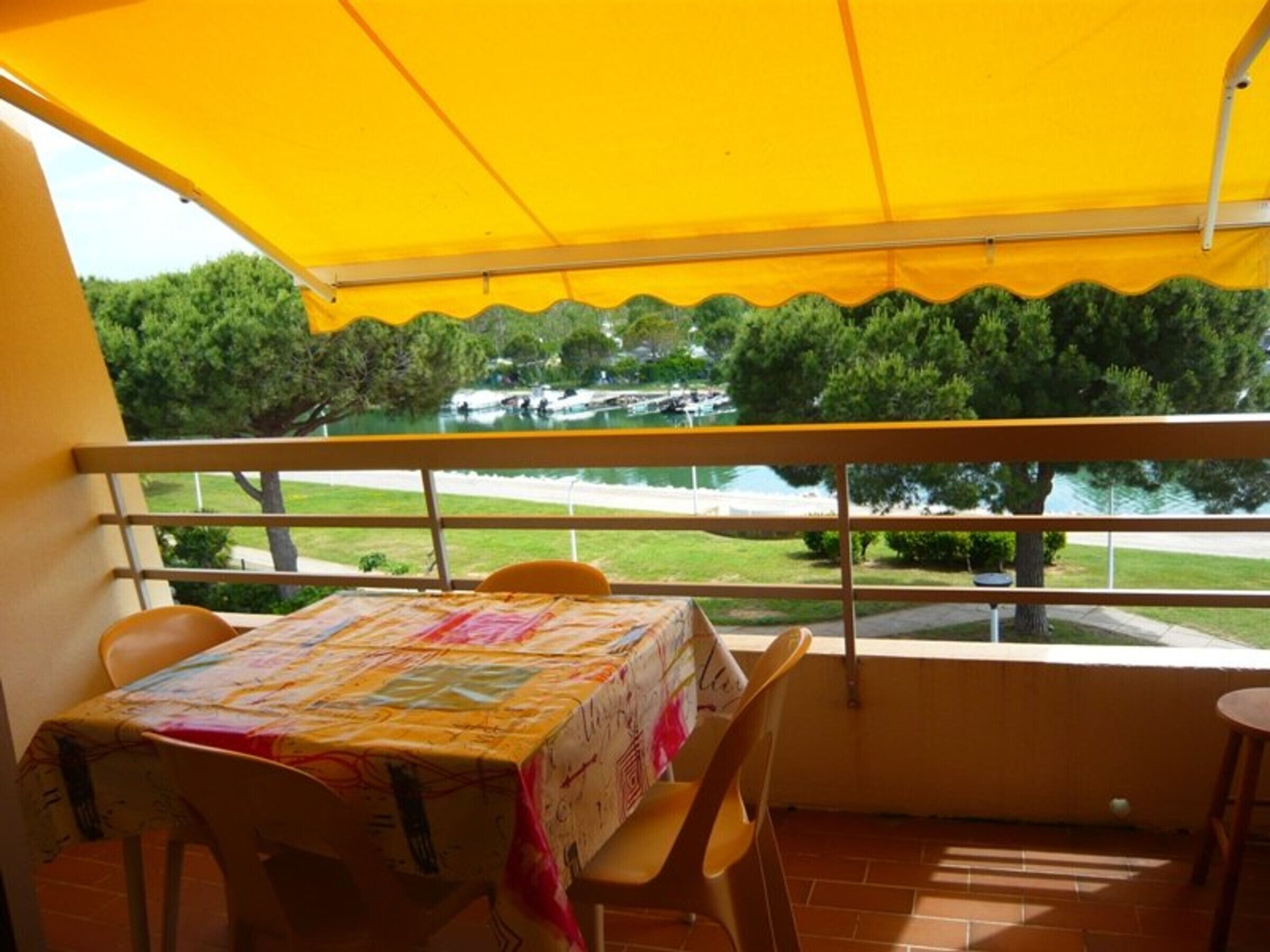 Ein Balkon mit gelbem Baldachin, einem Tisch mit bunten Tischdecken und Stühlen.