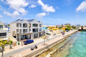 A coastal residential area with modern houses, a clear blue sky, and a calm sea.