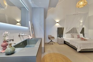 A modern bedroom with a large bed, bedside table, and a bedside lamp.