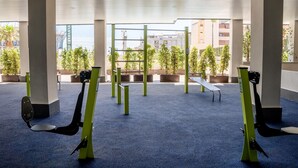 An indoor gym with exercise equipment, a blue carpet, and a view of buildings and trees outside. - Mijas Easy Flat With Pool - Ref 251 (Mijas)