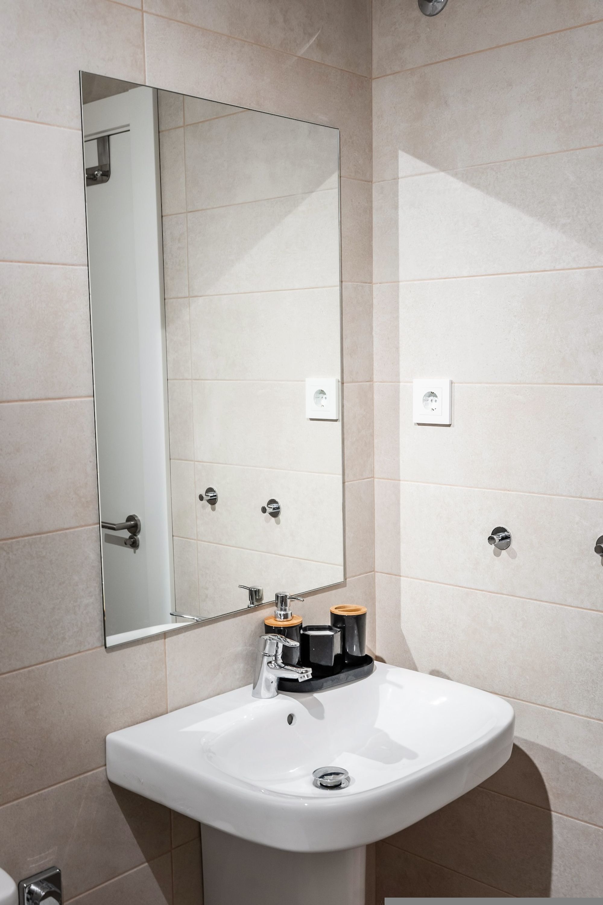 A bathroom with a white sink, a mirror, and a towel rack.
