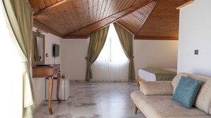 Un dormitorio con techo de madera, cama, sofá, escritorio y espejo.
