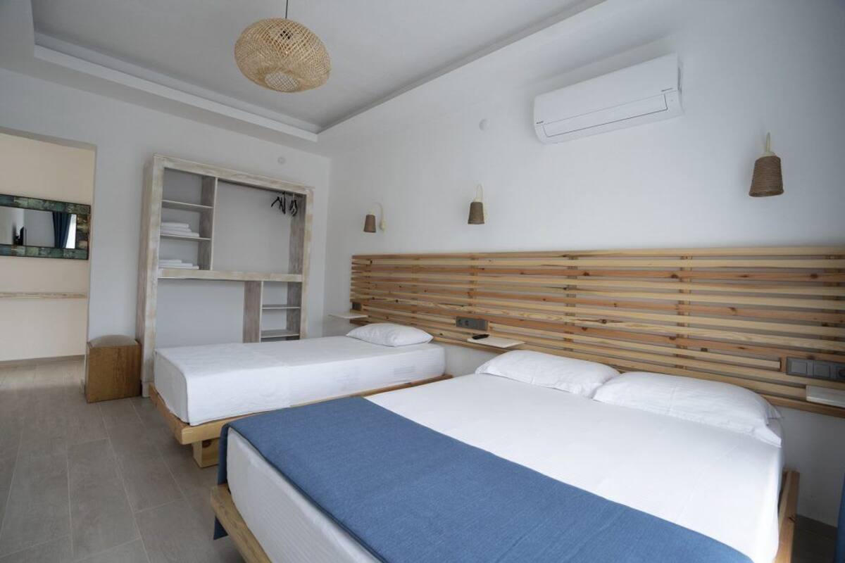 A bedroom with two beds, a wardrobe, a mirror, and a hanging light fixture.