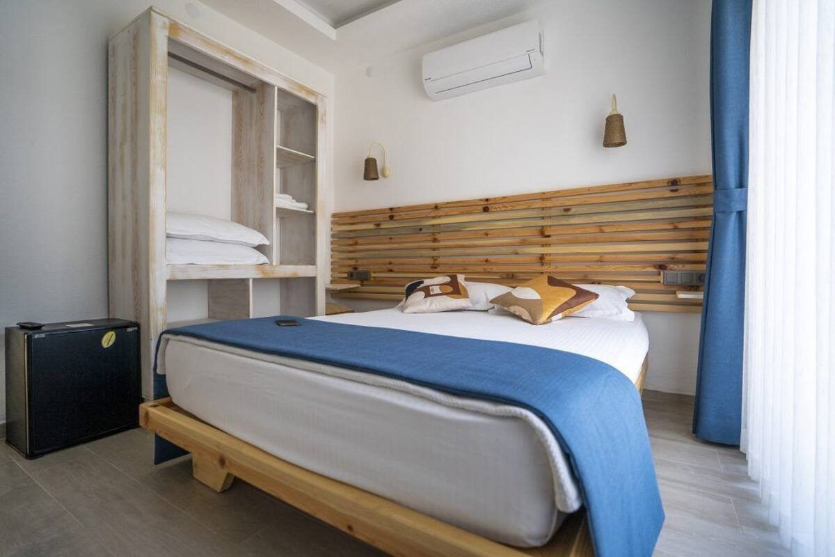 A neatly arranged bedroom with a bed, a wardrobe, and a suitcase.