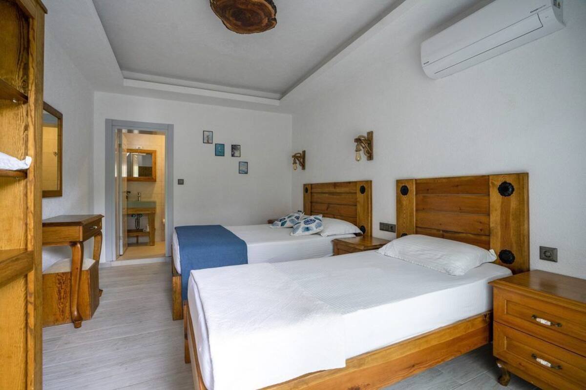 A bedroom with two wooden beds, a wooden desk, and a mirror.