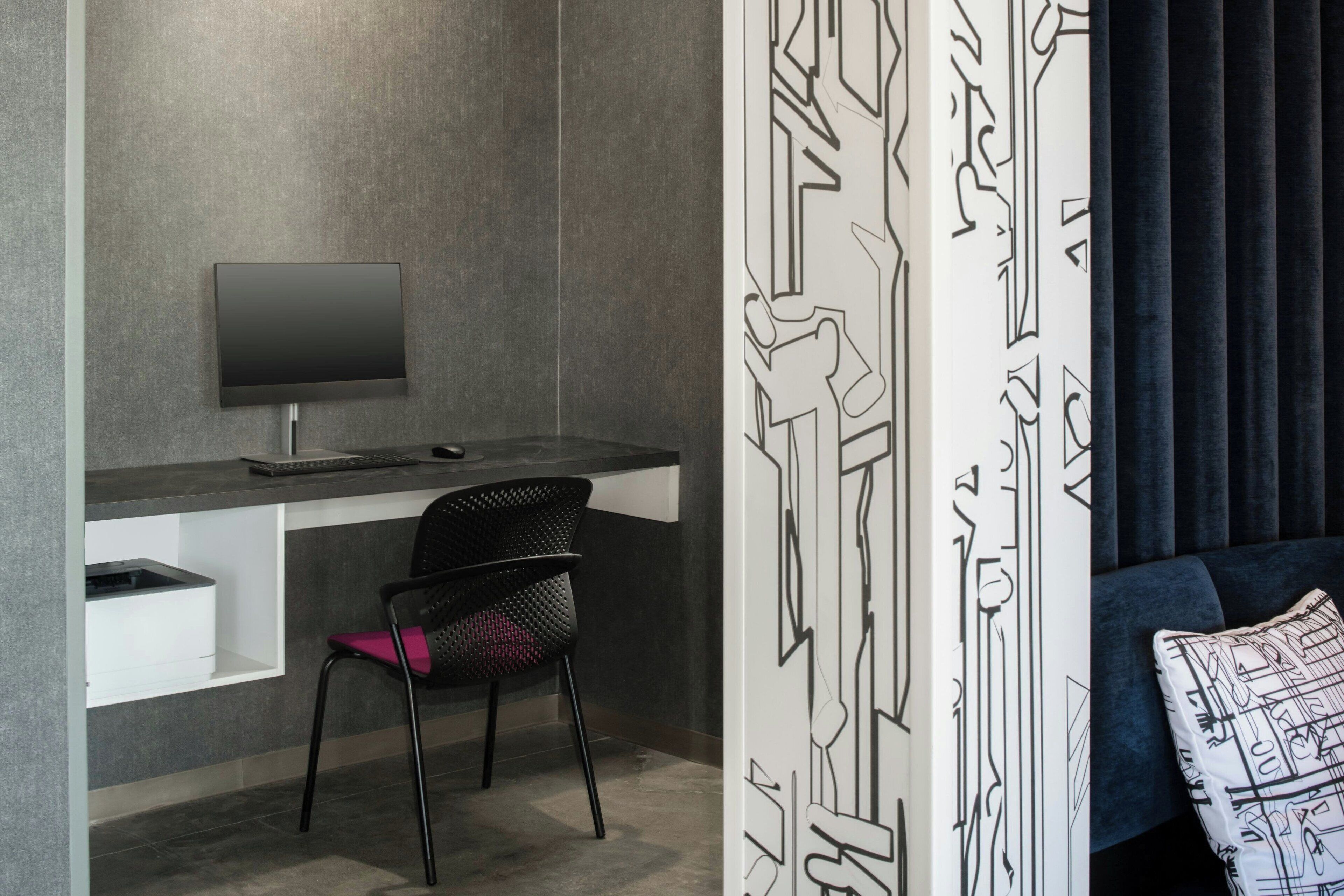 Una habitación moderna con escritorio, silla y un televisor grande.