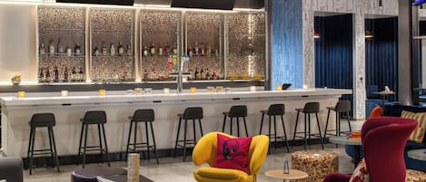 A bar area with a neon sign, a variety of bottles, and bar stools.