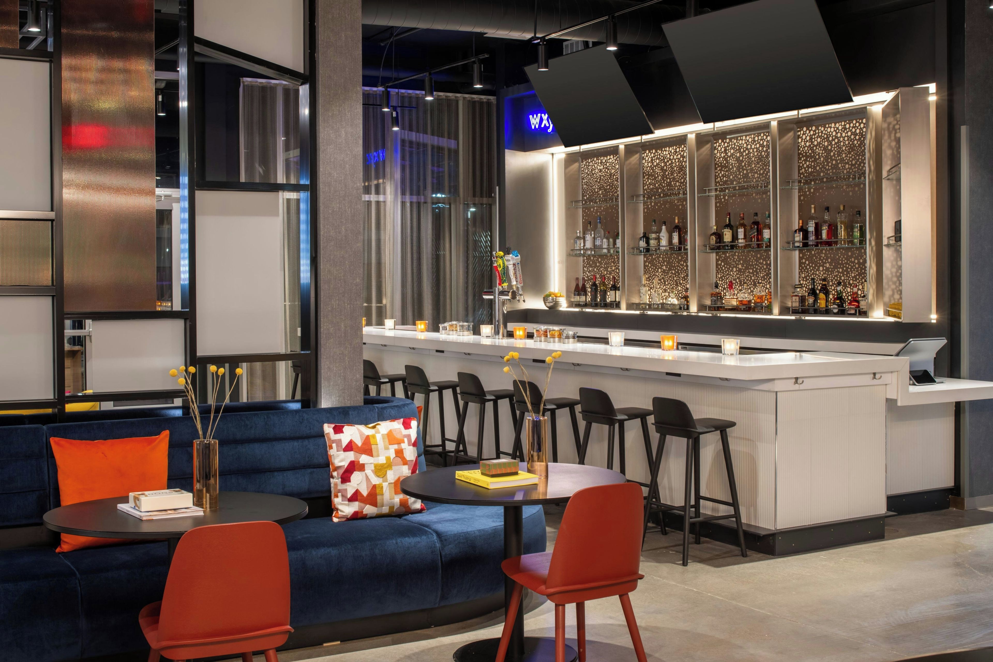 Un área de bar moderna con mostrador, asientos y una pared decorativa.