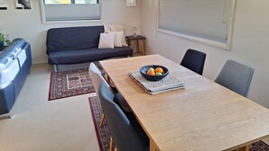 Ein modernes Wohnzimmer mit einem dunkelgrauen Sofa, einem Holzesstisch mit einer Obstschale und einem gemusterten Teppich.