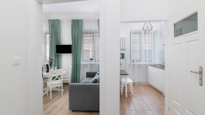 A modern apartment with a dining area, a living room with a grey sofa, and a kitchen with white cabinets. - EASY RENT Apartments- OLD TOWN (Lublin)