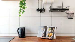 A kitchen with a coffee maker, a magazine rack, and hanging kitchen utensils. - EASY RENT Apartments- OLD TOWN (Lublin)