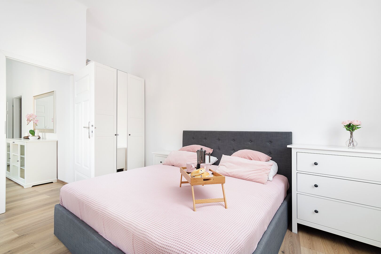 A bedroom with a bed, bedside table, dresser, and wardrobe.