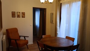 Un comedor con una mesa redonda de madera y seis sillas, un radiador y una lámpara en el techo.