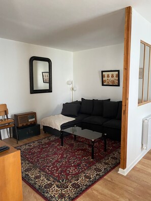 Relax in this stylish living room with a black sofa, glass coffee table, and cozy rug.