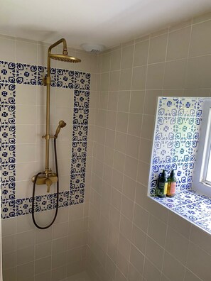 Enjoy a refreshing shower with a handheld shower attachment and gold showerhead, surrounded by a stylish tile pattern.