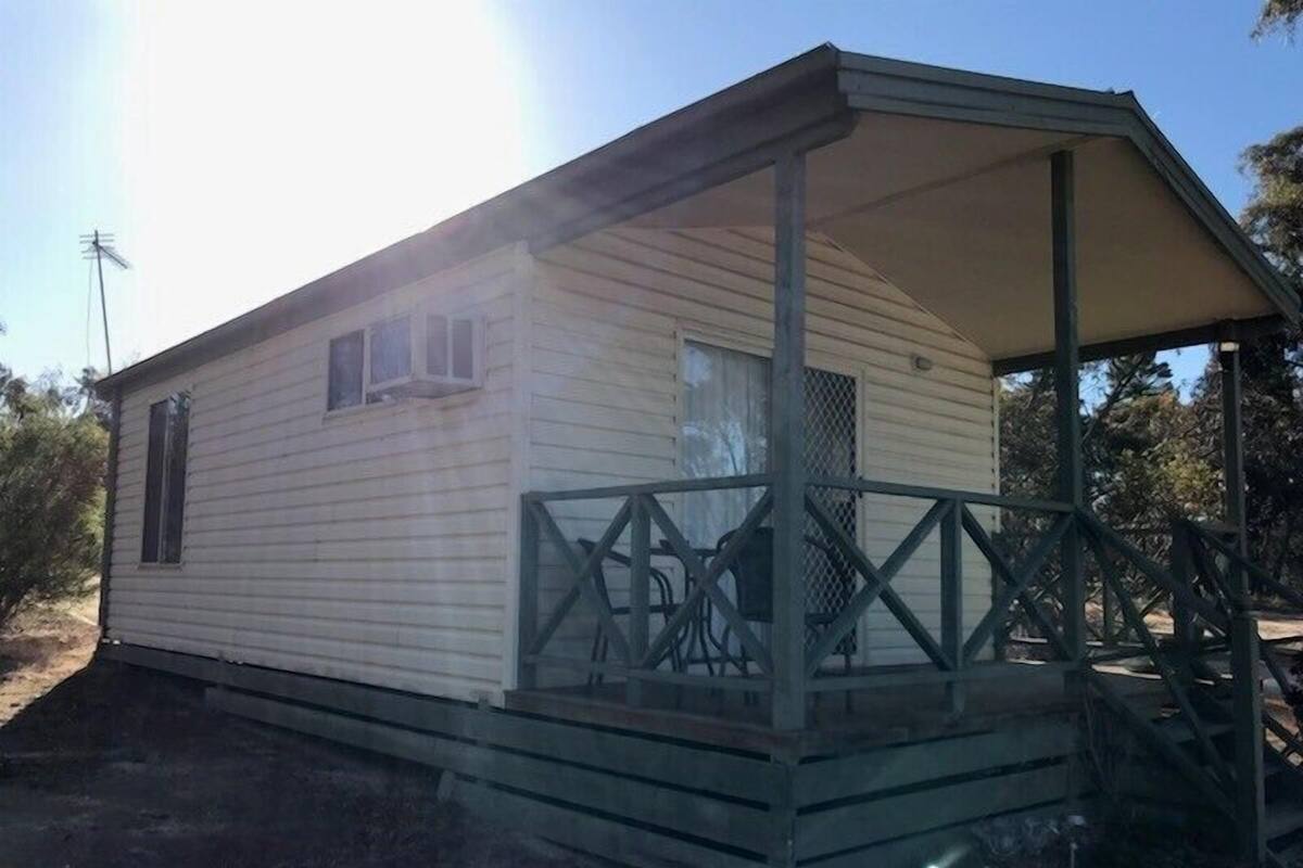 A single-story mobile home with a covered porch and a fenced area.