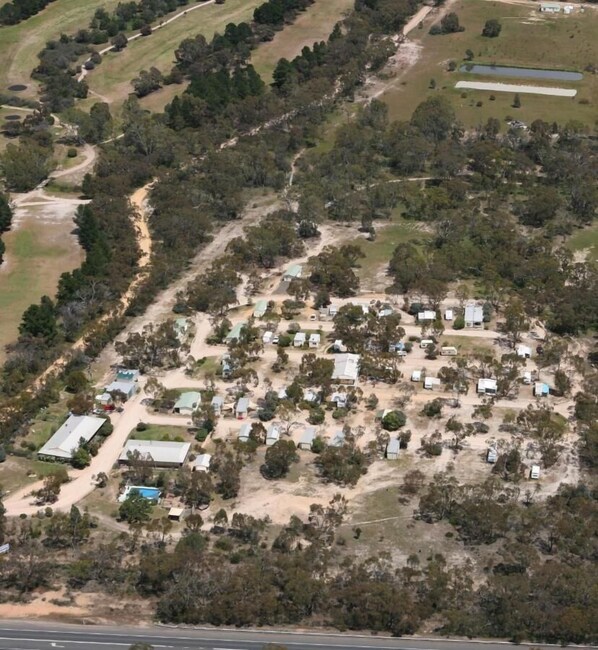 An aerial view of a campground with numerous RVs and cabins, surrounded by trees and open grassy areas. - Stawell Caravan Park (Black Range)