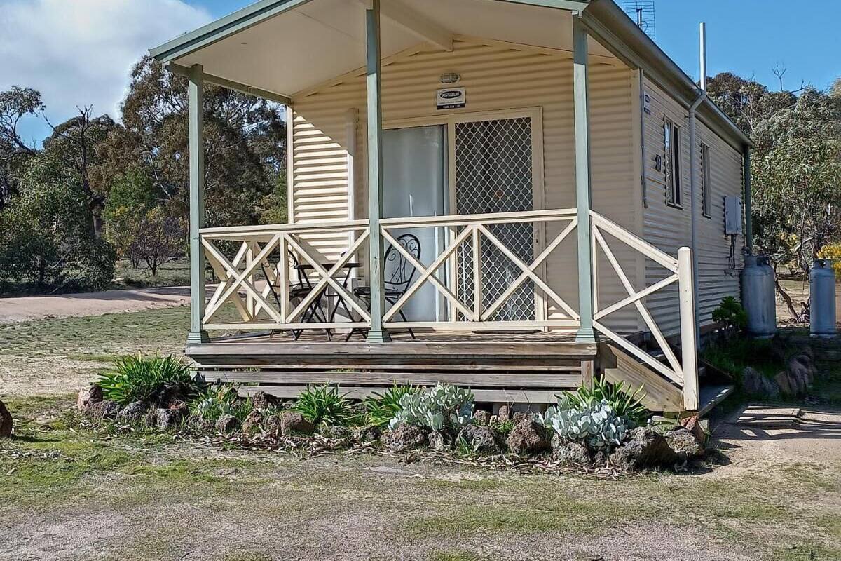 A small, single-story cabin with a porch and a covered seating area.