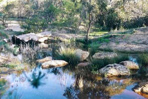 A natural landscape with a pond, rocks, and vegetation. - Stawell Caravan Park (Black Range)