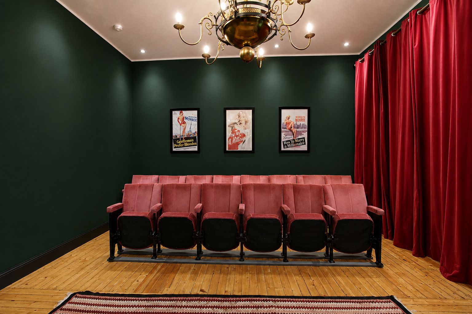 A theater with red velvet seats, a wooden floor, and a chandelier.