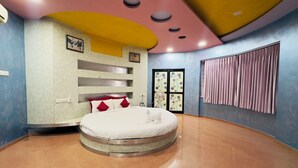 Een moderne slaapkamer met een rond bed, inbouwkasten, een plafondventilator en een raam met gordijnen.