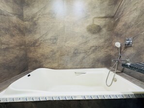 Ein Badezimmer mit einer weißen Badewanne, einer Dusche und einer Marmorwand.