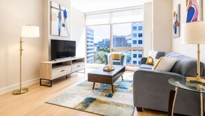 A modern living room with a sofa, TV, and floor lamp. - Luxury Apt Near Downtown (Stamford, CT)