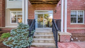 A brick building with a front entrance, a small staircase, and a potted plant. - Luxury Modern Apt with Patio (Lexington, MA)
