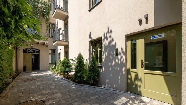 A courtyard with a paved walkway, a green door, and a sign for Orient Hotel.