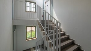 A staircase with a white railing leading to a landing with a skylight.
