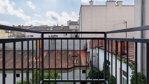 A balcony with a metal railing overlooking a residential area with buildings and a clear sky.