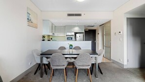 Un moderno comedor con una mesa rectangular, cuatro sillas tapizadas grises con patas de madera y una pequeña planta en maceta sobre la mesa.