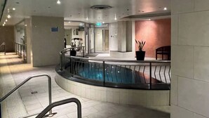 Zona de piscina con diseño circular, área de descanso con una planta en maceta y una escalera que conduce a otro nivel.