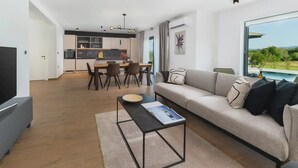 Ein modernes Wohnzimmer mit einer Couch, einem Couchtisch und einem Essbereich mit Stühlen und einem Tisch.