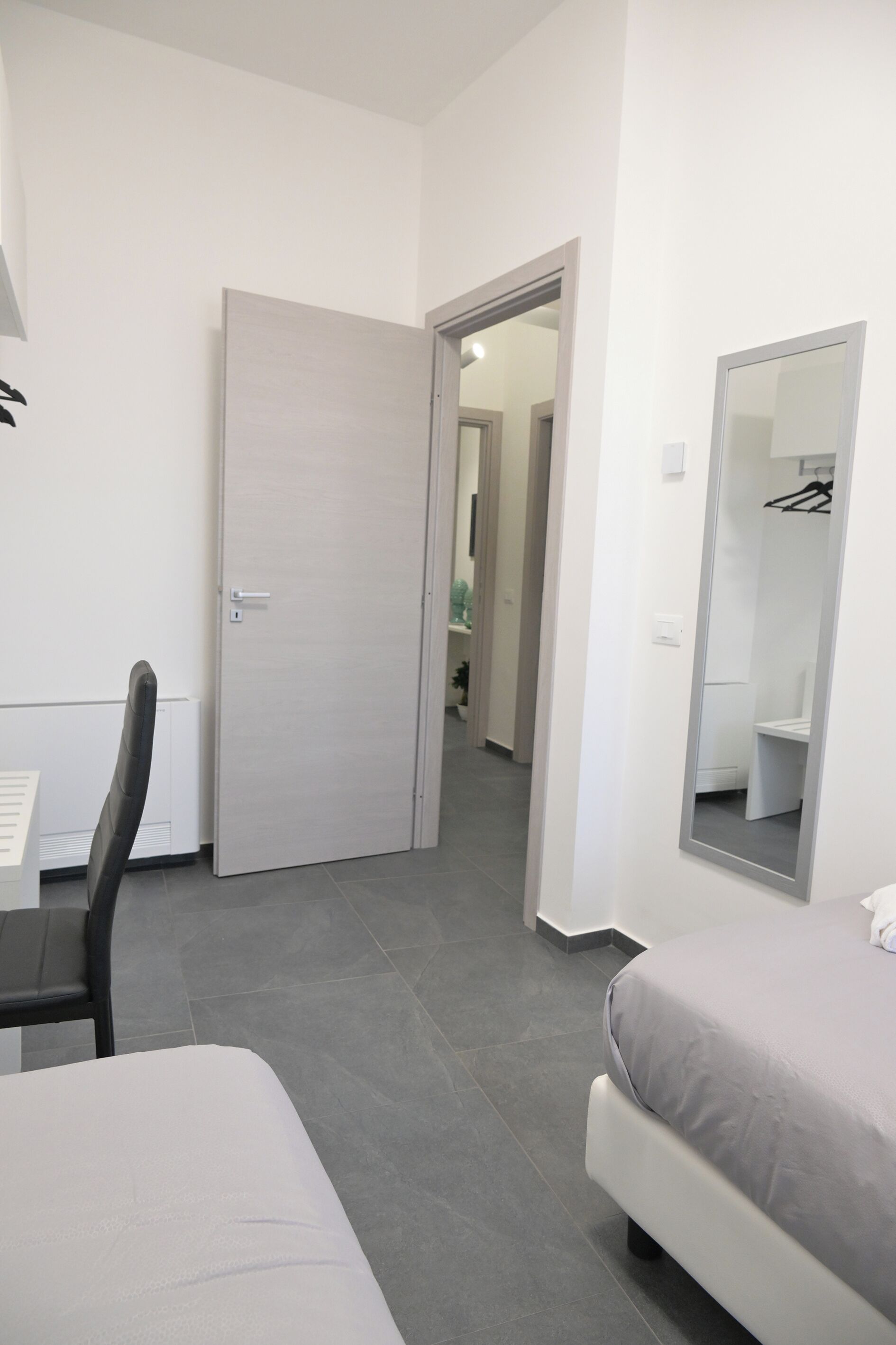 A modern bedroom with a bed, a chair, a desk, and a wardrobe.