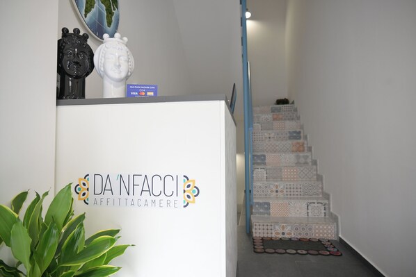 A reception desk with a logo and a staircase with patterned tiles.