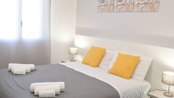 A modern bedroom with a large bed, two bedside lamps, and a window with curtains.