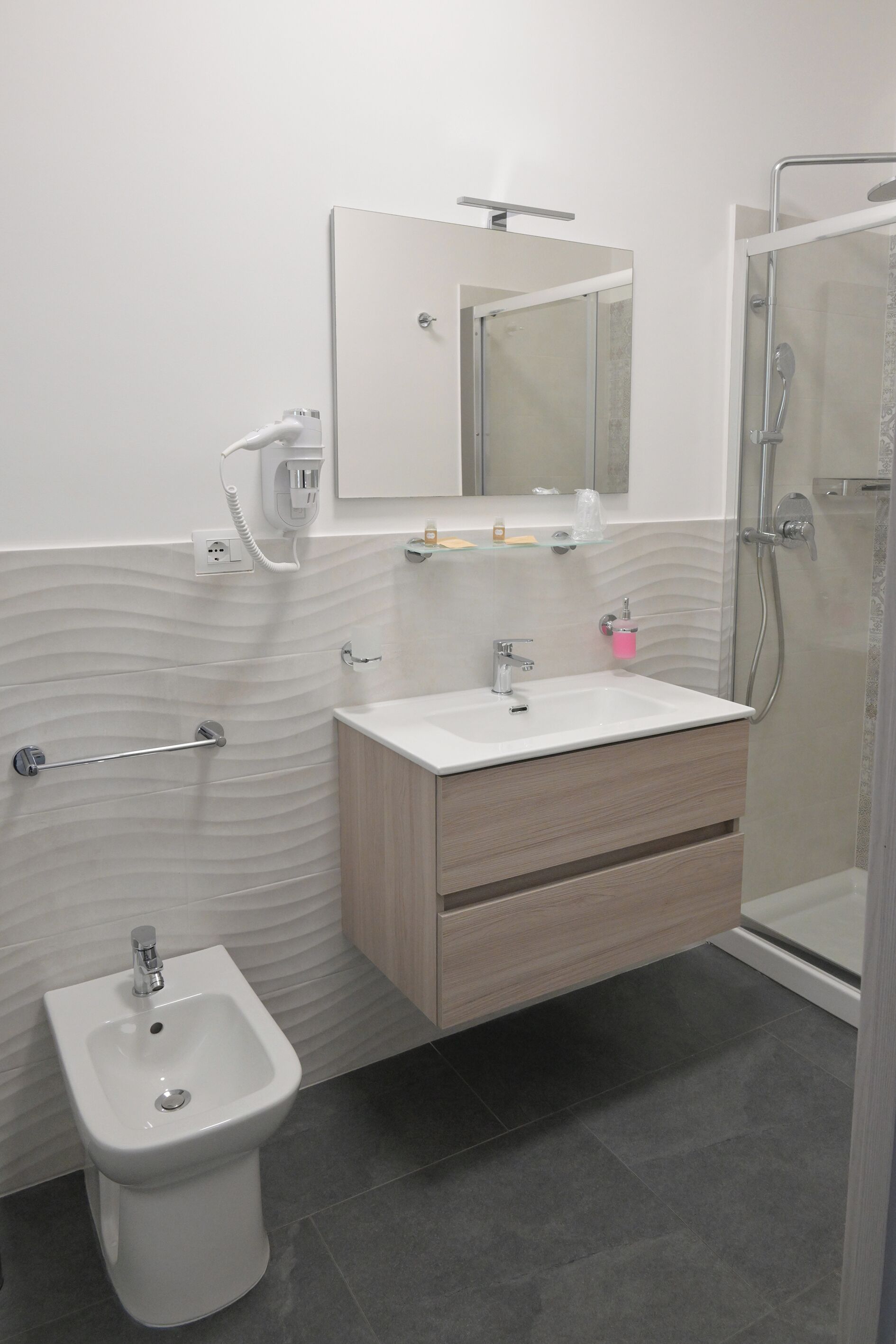 Une salle de bain moderne équipée d’un bidet, d’un lavabo et d’une douche.