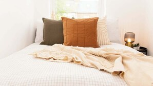 A neatly made bed with a patterned bedspread, a beige throw blanket, and several pillows. - Charming fully furnished 2-bedroom home (Nottingham)
