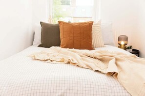 A neatly made bed with a patterned bedspread, a beige throw blanket, and several pillows. - Charming fully furnished 2-bedroom home (Nottingham)
