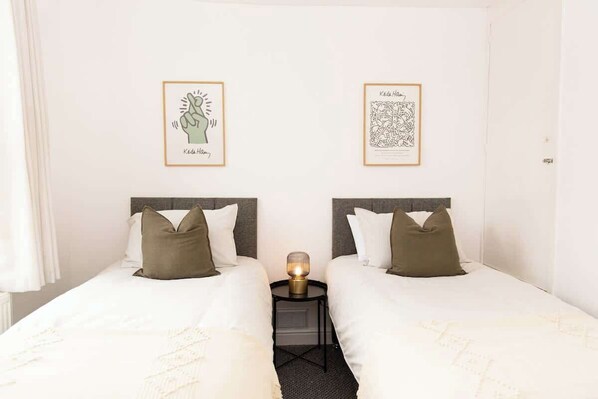 A double room with two beds, a bedside table, and two framed artworks on the wall.