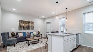 A modern living room with a sofa, coffee table, and artwork on the wall. - Suite 2 on Southport 4 Queen Beds (Chicago)