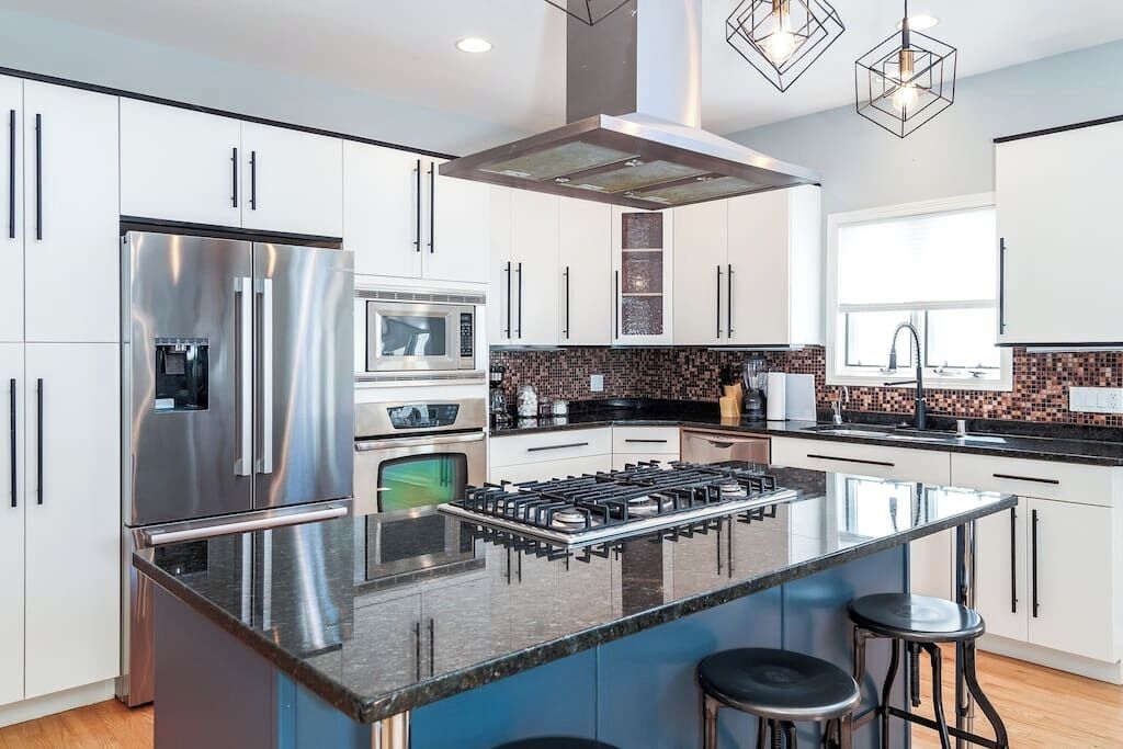 A modern kitchen with stainless steel appliances, a central island, and a black countertop.