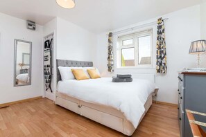 A bedroom with a bed, a dresser, a mirror, a window with curtains, and a radiator. - Inviting and Cosy Annexe | Free Parking and Wi-Fi (Nottingham)